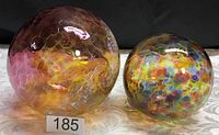 Photo showing a large and medium hand blown glass witch's balls with iridescent finishes in honeycomb and mottled patterns.