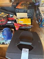 Photo of black portable speaker with handle on top surrounded by other items