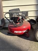 Front view of red Porter-Cable air compressor showing 135 PSI label and attached pressure gauges and control valve.