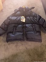 Front view of the black XL puffer jacket showing big zipper, two side pockets, and a tag attached.