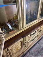 Photo shows wooden hand-carved fish figurines painted in vibrant colors inside a vintage glass front cabinet with ornate trim.