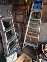Photo shows both the Little Giant aluminum ladder folded, the metal step ladder standing open with blue plastic top, and the red dolly behind the ladders.