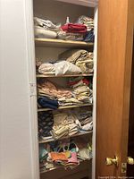 Shelves in a closet filled with folded sheets and towels in various colors and patterns.