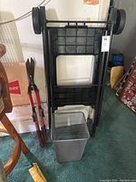 Photo of Ninja food stand showing the wheels, molded sections, and rectangular opening, with wastebasket in front.