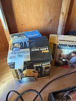 Three Wagner Power Painter spray kits in original boxes on wooden shelf.