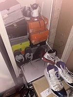 Closet corner overview showing stacked shoeboxes, various sneakers and a pair of dress shoes on floor