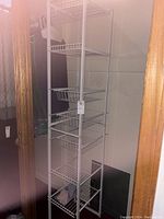 Photo of tall white wire shelf closet organizer with five wire shelves in a closet space.