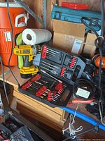 DeWalt cordless drill with attached battery and a case open showing various drill bits and screwdriver bits.