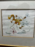 Framed thread embroidery artwork portraying a Chinese dragon with clouds and wave patterns on fabric.