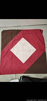 Full view of oversized pillow case showing red and brown quilted fabric with central white embroidered panel.