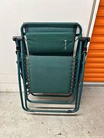 Folded zero gravity chair showing frame, fabric, and headrest with wear and stain.