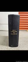 Photo showing the spine of the book with black textured cover and gold title 'Petit Larousse en Couleurs'.