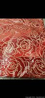 Close-up photo showing red pillow case with detailed embossed gold rose pattern.