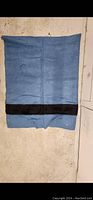 Full view of the blue wool blanket with a visible hole and a black stripe.