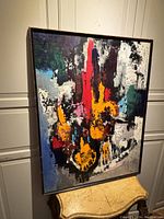 Full front view of framed abstract painting leaning against cabinet