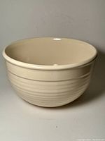 Front and side view of the cream Emile Henry ceramic mixing bowl on a white background.