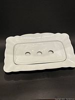 White rectangular porcelain tray with scalloped edges and a separate draining plate with three holes resting inside.