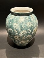 Front view of the bulbous green and white leaf-patterned vase showing its shape and detailing.