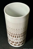 Top and side view of white porcelain cylindrical vase with gold geometric pattern on black background