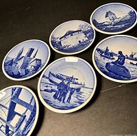 Six small blue and white ceramic coasters showing detailed Danish buildings and landmarks in scenic designs.