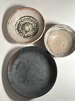 Overview of three signed pottery dishes in complementary rustic tones, sizes 9, 7, and 6 inches