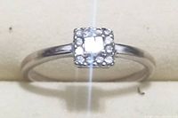 Close up front view of thin white gold ring with square cluster diamond setting showing diamond sparkle and band shape.