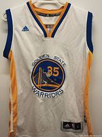 Front view of a white Adidas Golden State Warriors basketball jersey with blue and yellow trim and #35 on the front, size Large tag visible.