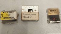 Three packaged needle items including Shure N-95Ej plastic case, Box labeled Gramophone Needles, Tonar Diamond phonograph needle case.