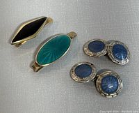 Photo showing two guilloche enamel tie clips, one turquoise and one black, and two pairs of blue guilloche enamel cufflinks set in sterling silver.
