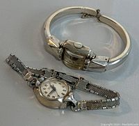 Two vintage wrist watches, one with a bangle style band and rectangular face, the other with a mesh band and round face.