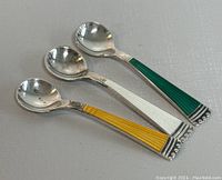 Three sterling silver mini spoons with guilloche enamel handles in yellow, white, and green arranged side by side for clear view of spoon bowls and handles.