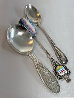Photo of all three sterling silver collectible spoons with one plain silver and two with enamel Lake Louise Canada and Alberta crest designs.