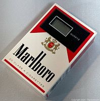 Front view of the Marlboro cigarette pack-shaped digital quartz clock, showing the digital display labeled 'Quartz' and Marlboro branding.
