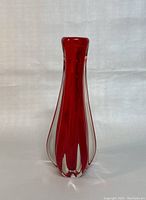 Full view of the tall red and clear hand blown glass vase with bulbous body and narrow neck, showing the elegant shape and color.