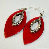 Top view of both red coral marquise-shaped earrings with decorated silver mounts and hooks.