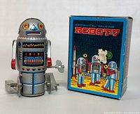 Metallic silver robot toy with colorful printed circuit and face designs next to its blue space-themed 'Mechanical Walking Robot-7' box.