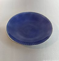 Top view of the small round dish showing deep blue guilloche enamel finish with radial pattern.