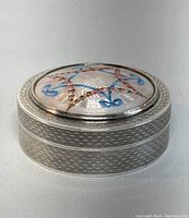 Side angle showing circular form and textured guilloché silver body