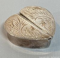 Heart-shaped sterling silver pill box closed, showing engraved lid.