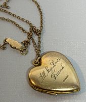 Front view of yellow gold filled heart locket pendant engraved 'All My Love Frank' with chain visible