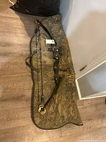 Full view of Martin M-7 Lynx compound bow laid on camo soft case on wooden floor.