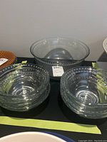 View of the large glass bowl with six smaller glass bowls nested beside it, all featuring raised dot patterns around the rims.