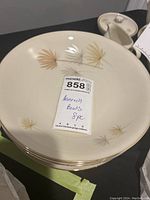 Eight cream-colored Heinrich bowls stacked, showing floral design and gold rim.