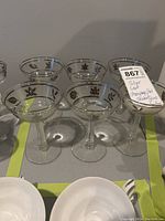 Six clear tall champagne/sherbet glasses with silver leaf decorative leaf patterns around the rim arranged in two rows.