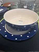 Overview of the bowl sitting inside the matching platter, showing deep blue color and white polka dots.