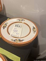 Stack of 6 vintage RW China dessert plates with orange luster rim and floral decoration, label showing lot number and details.