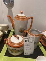 Full view of three-piece vintage RW tea set showing teapot, creamer, and sugar bowl with lids. Orange luster and floral patterns visible.