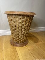 Large woven wood blanket basket with flared shape, round wooden base, and wide top rim.