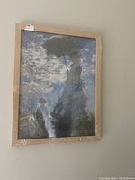 Front view of the Monet print in a light wooden frame hung on a wall, showing the full artwork scene.