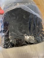 Bundle of black faux eucalyptus stems sealed in clear plastic packaging on a wooden floor.